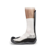 Talonette Pour Surélever Le Talon D'Achille Présenté De Côté Où On Voit Un Pied Dans Une Botte Orthopédique S'appuyant Là-Dessus